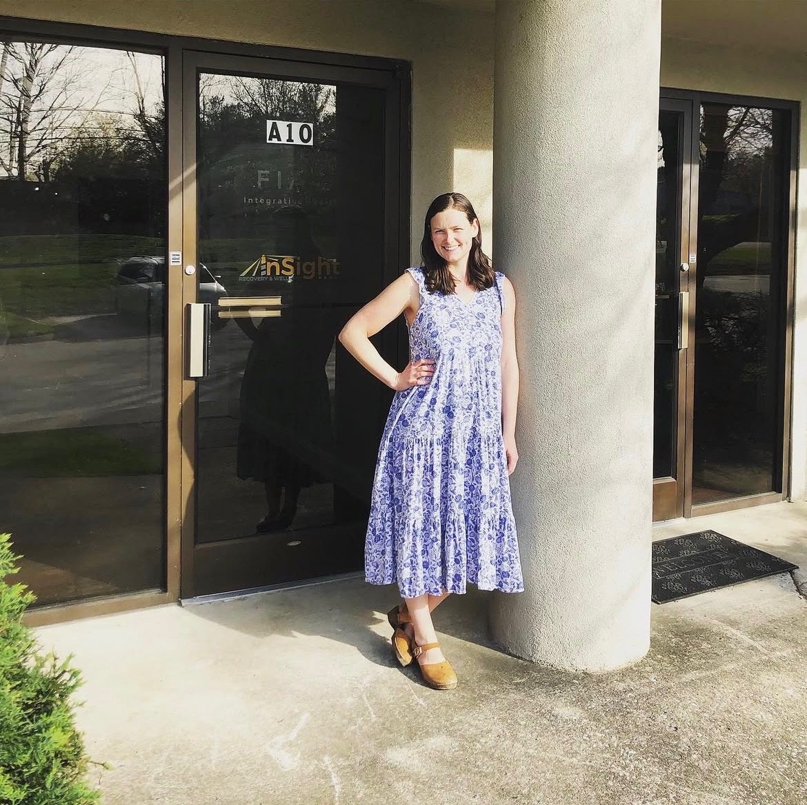 Caroline Hartley, FNP, smiling outside a Fiat Integrative Health office door