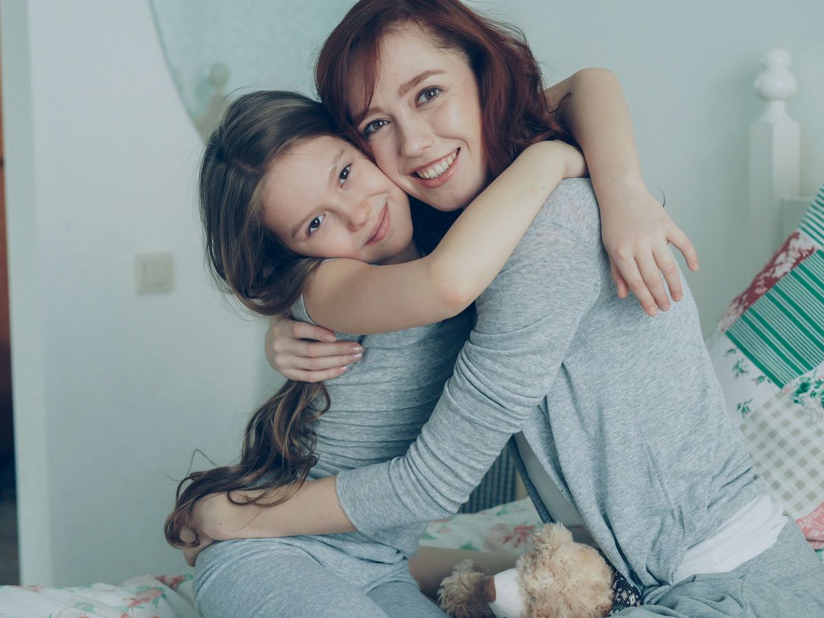 A smiling mother and daughter sharing a warm hug