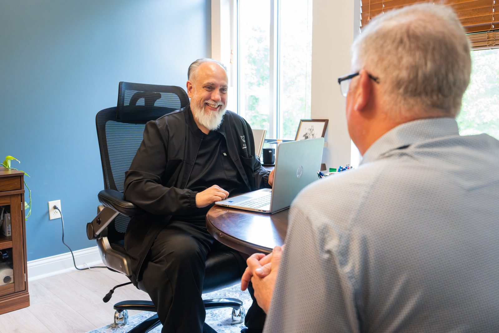 Dr. Ed Glynn smiling as he talks with a patient across his desk