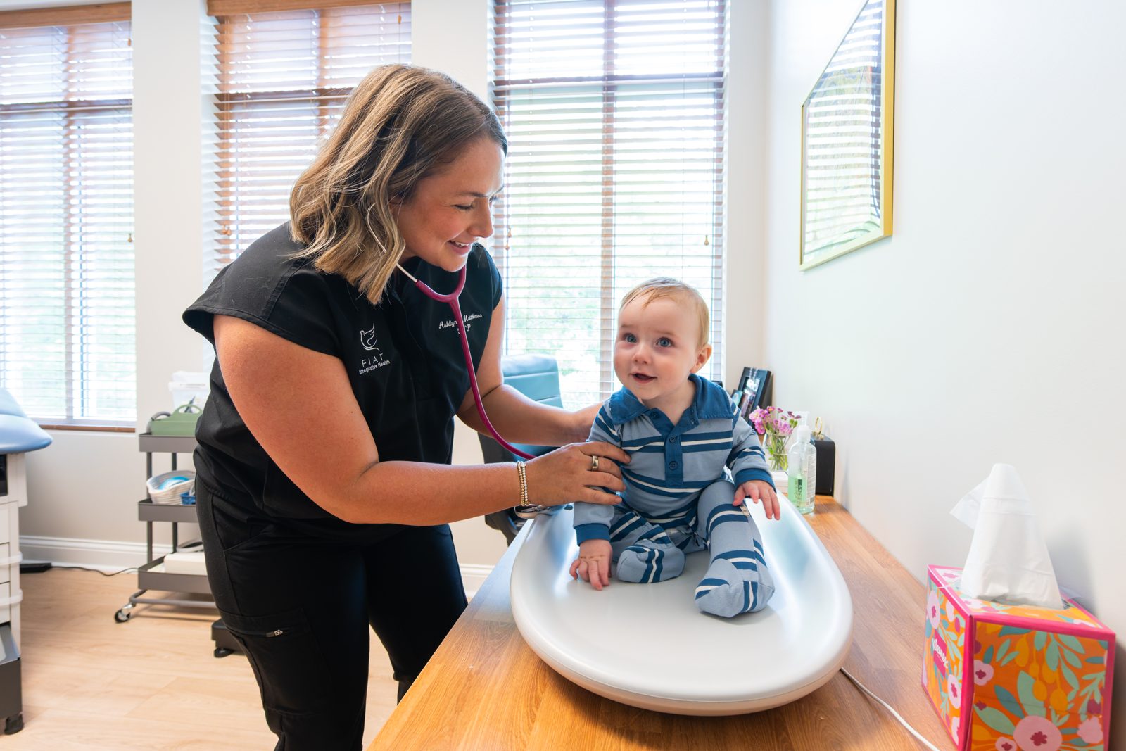 Ashlynn Matthews, FNP, listening to a smiling baby's heart during a visit